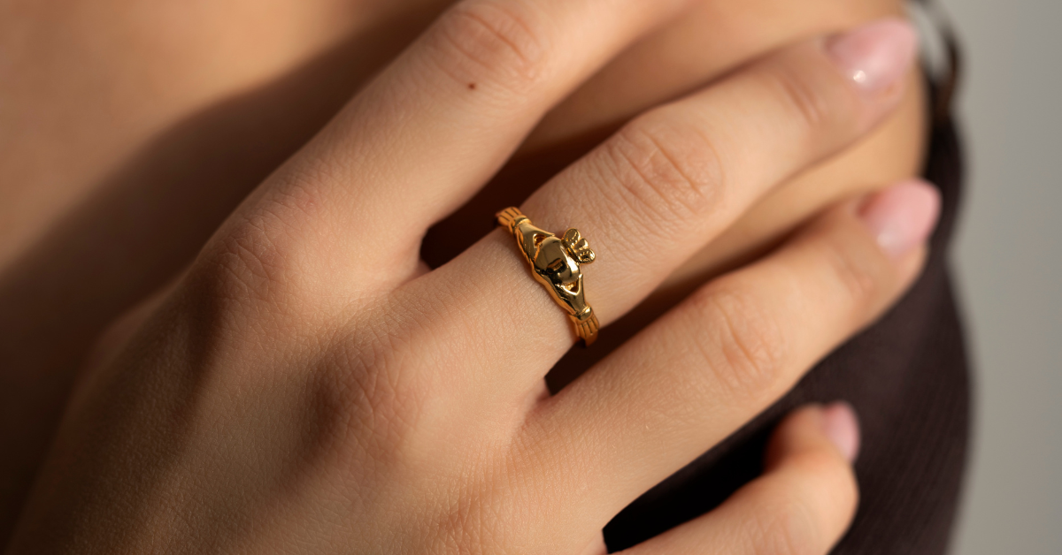 A gold Claddagh ring worn on a hand.