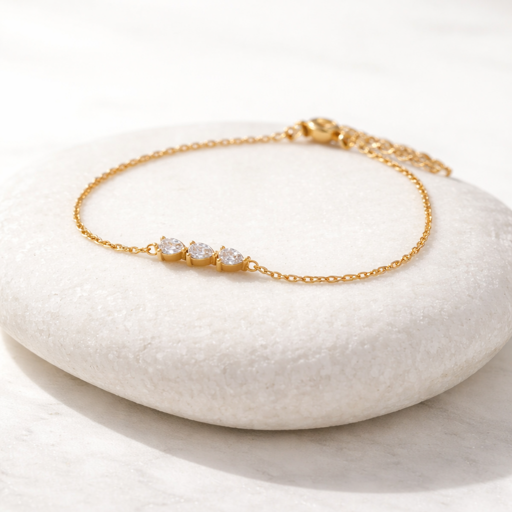 Gold bracelet with three stones on a white stone surface