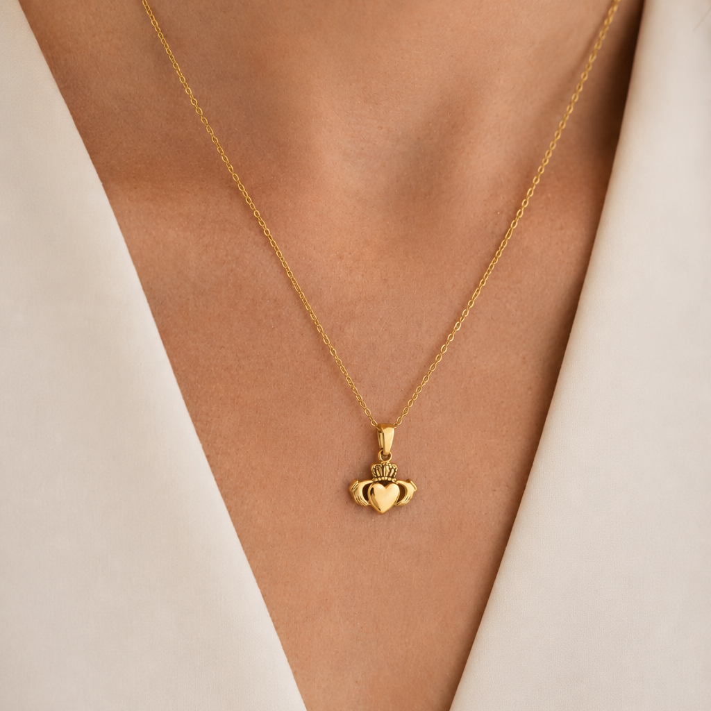 Gold necklace with a crown pendant on a person wearing a white outfit.