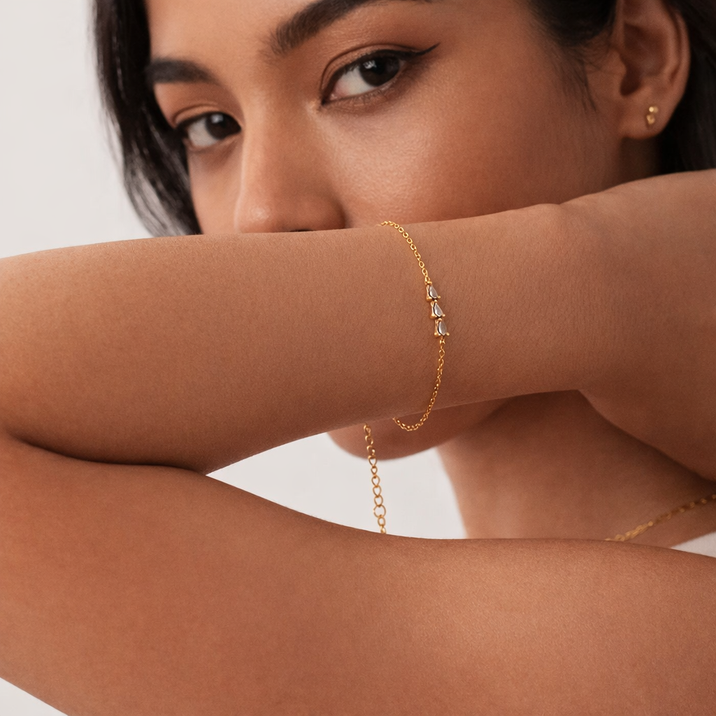 Close-up of a person wearing a gold bracelet on a plain background