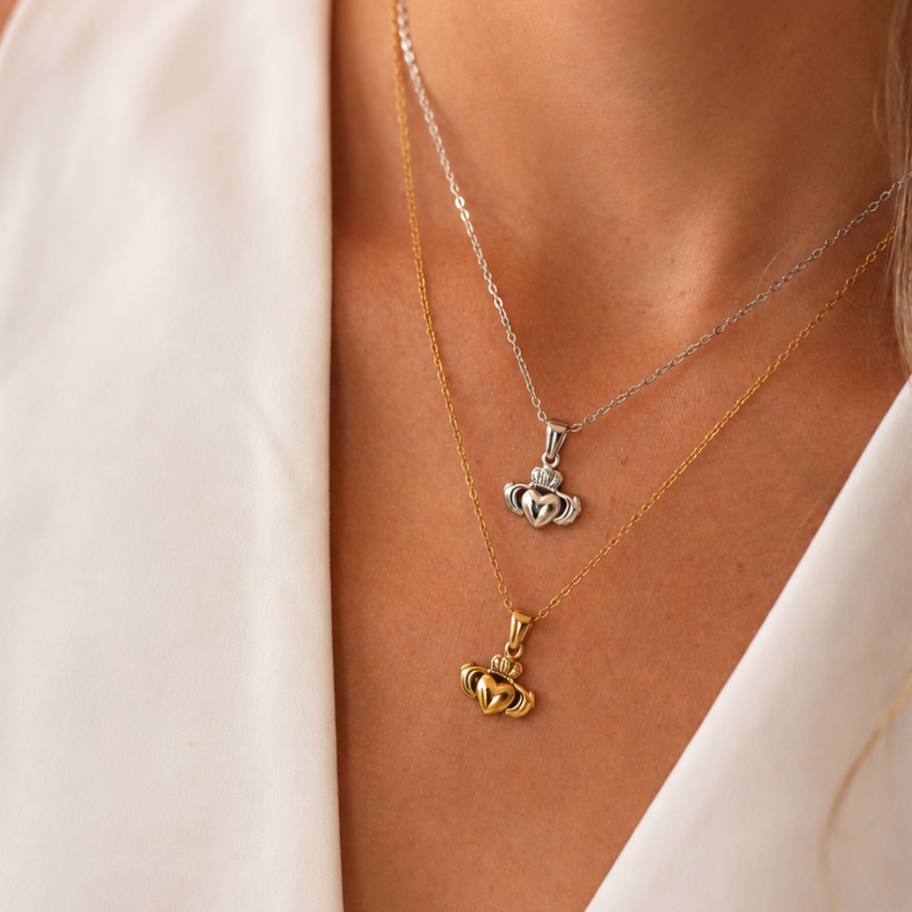 Two necklaces with crown pendants on a person wearing a white top.