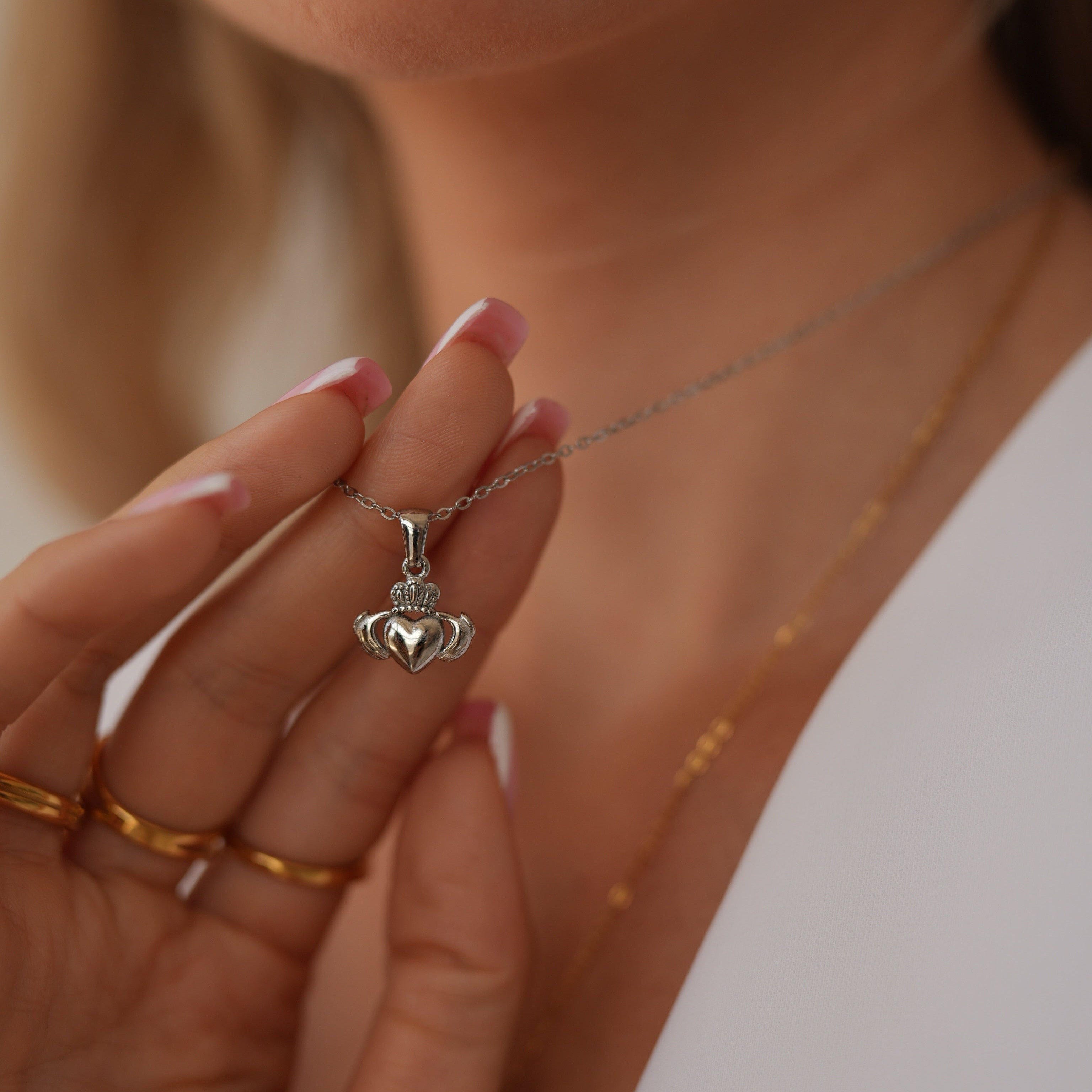 Close-up of a hand holding a silver necklace with a pendant.