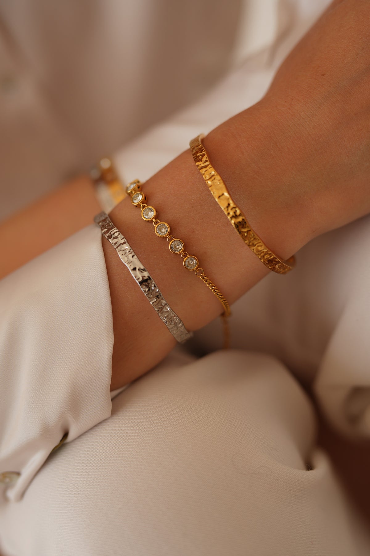 Bracelets and cuffs styled together on a wrist.