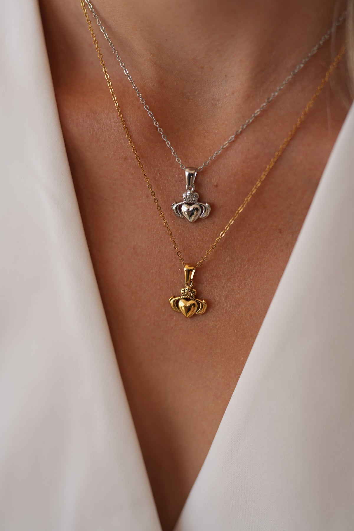 Colliers à pendentif Claddagh doré et argenté portés ensemble.