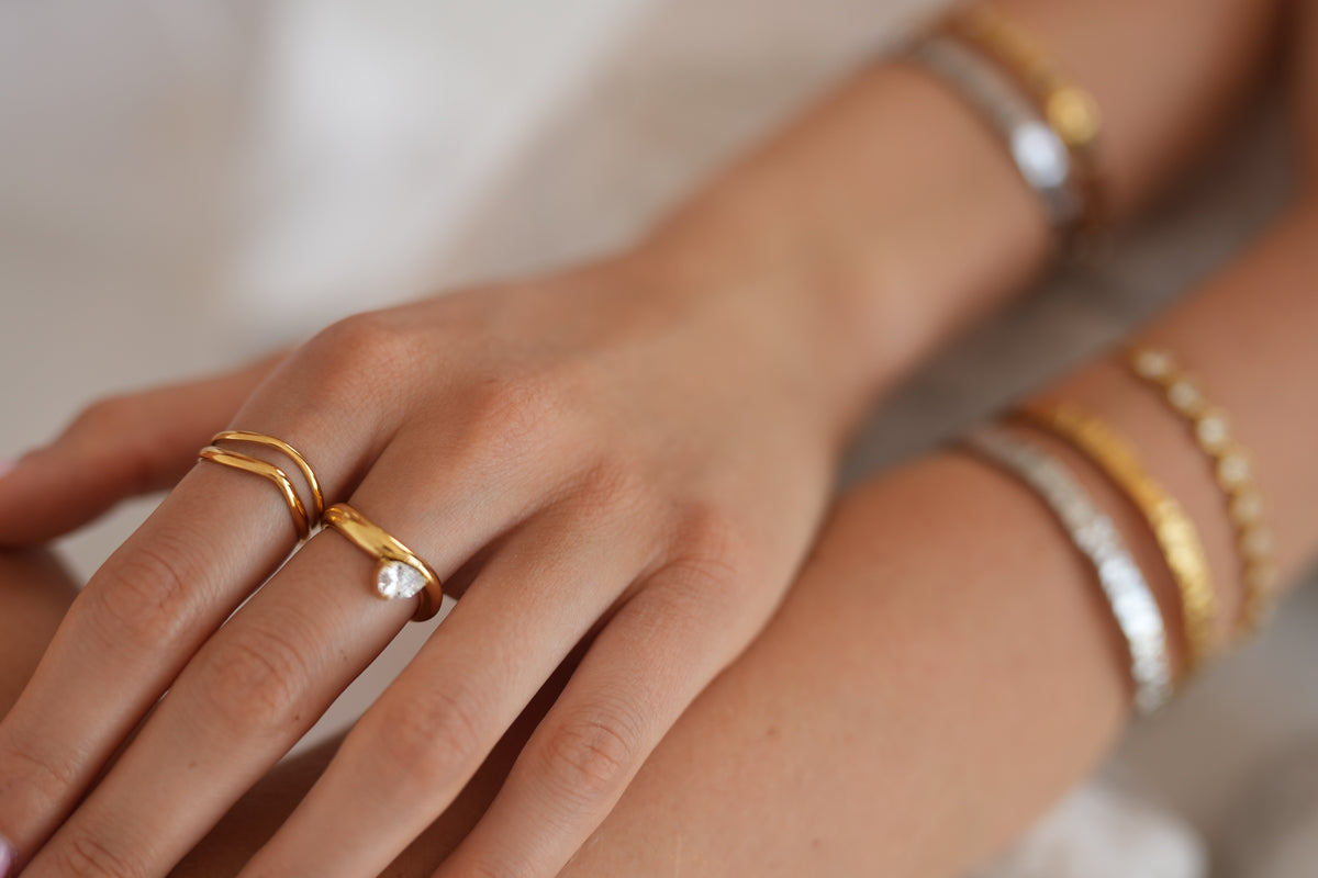 Gold rings worn together, showing their different shapes and textures.
